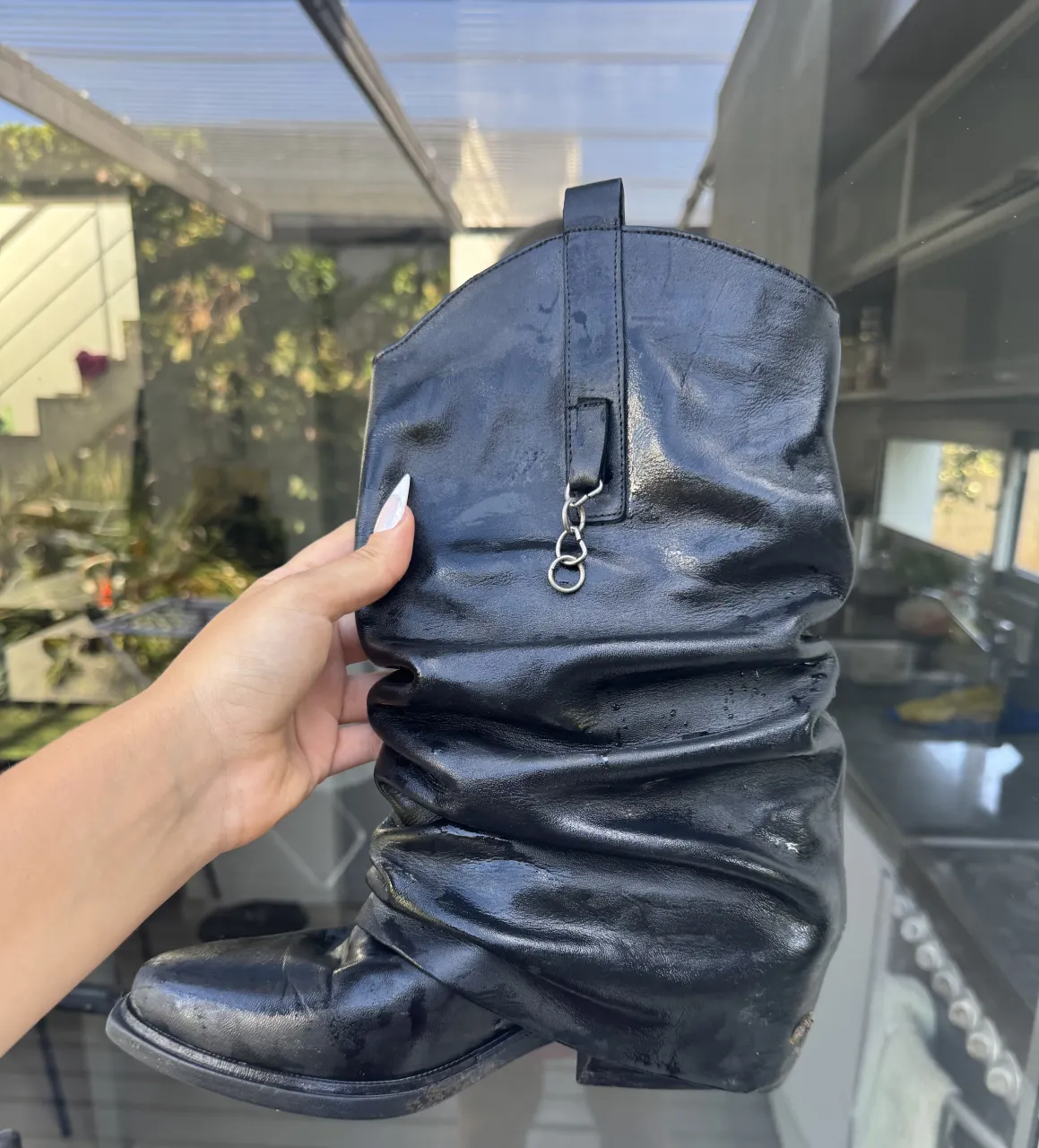 Botas de cuero negras con diseño arrugado y detalle de dos argollas plateadas unidas en la parte superior. Están como nuevas 