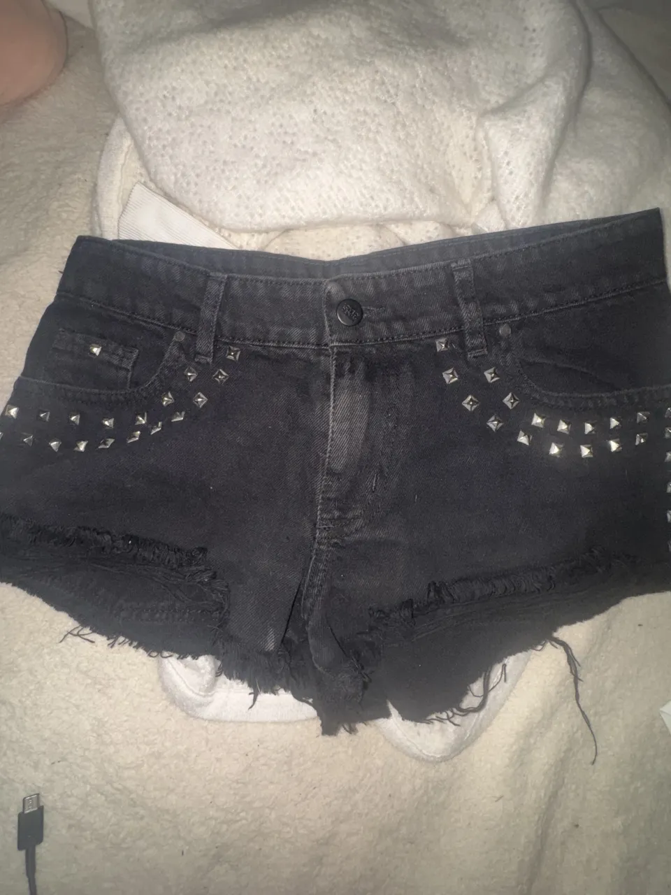 LOVELY DENIM.
TALLE 28 :Shorts de jean negros con tachas plateadas y roturas. Un básico con un toque rockero para darle onda a cualquier look.