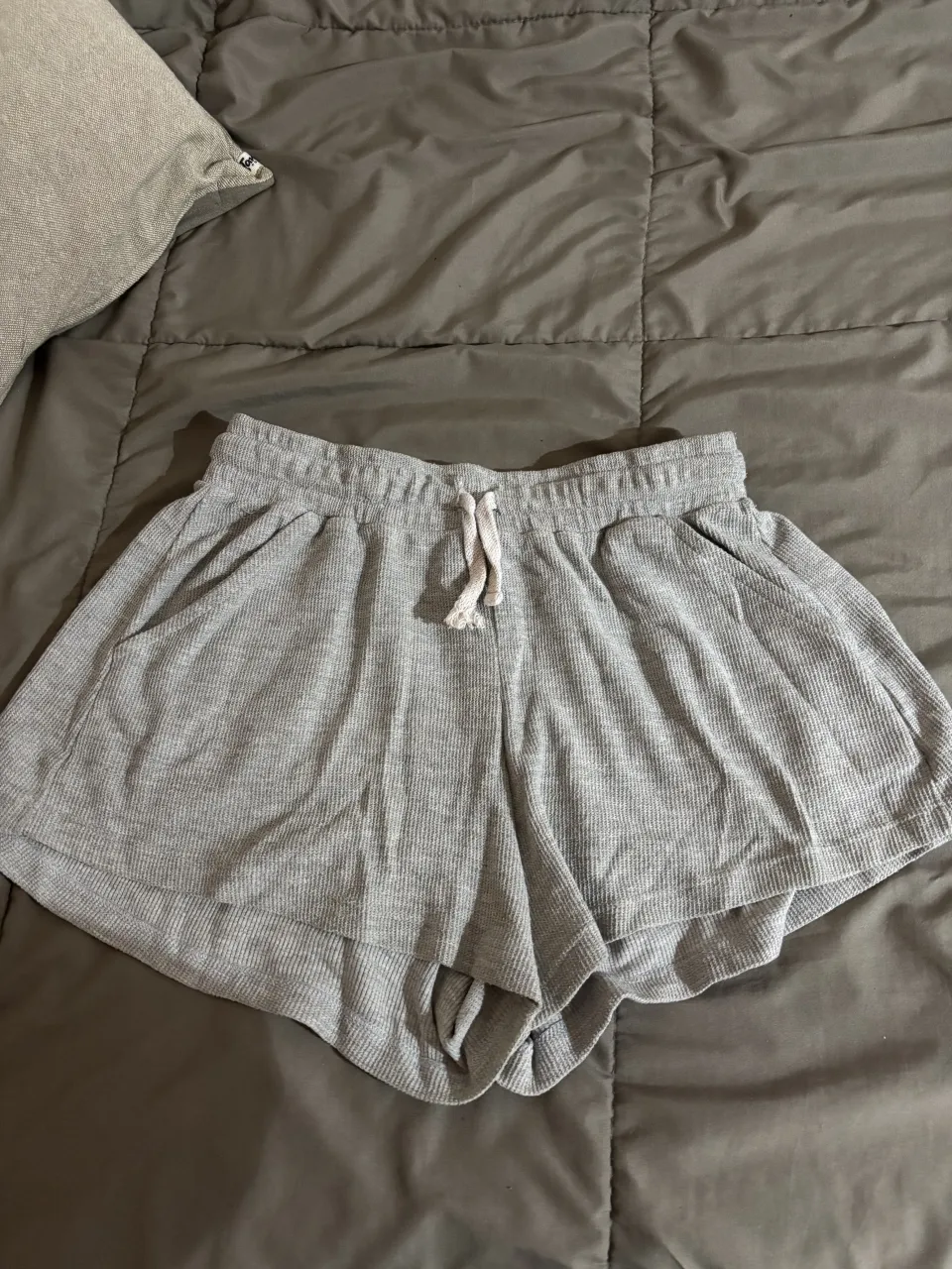 Shorts gris, tipo pijama súper cómodos. Tienen cordón ajustable en la cintura y bolsillos laterales. Ideales para estar en casa o para un look relajado.