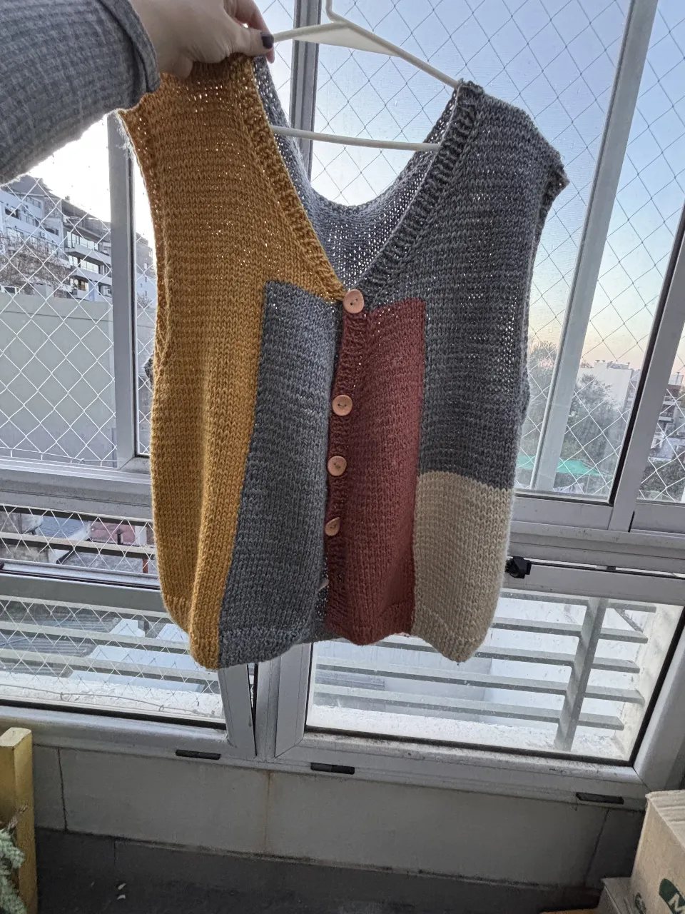 Chaleco tejido a mano con diseño patchwork en tonos amarillo, gris, marrón y beige. Ideal para un look casual y abrigado.
