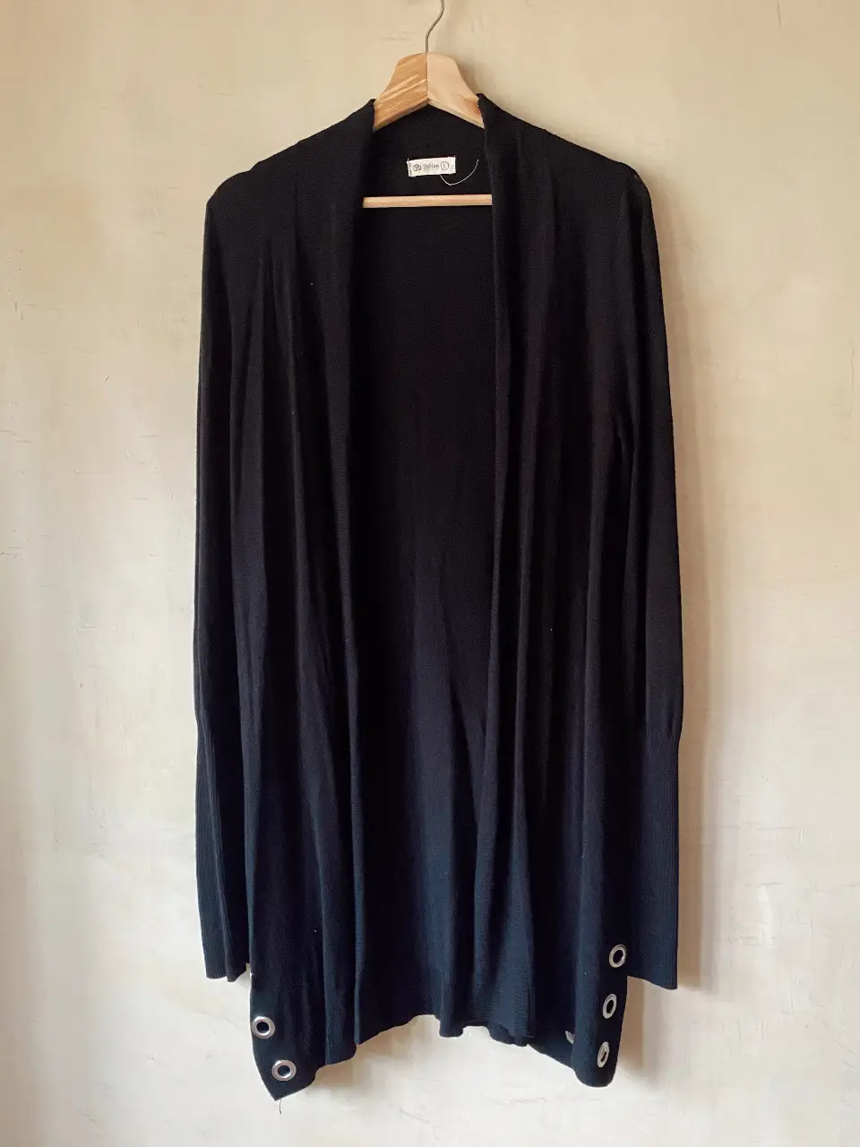Cardigan largo negro con detalles de ojales metálicos en los laterales. Ideal para un look casual y versátil.