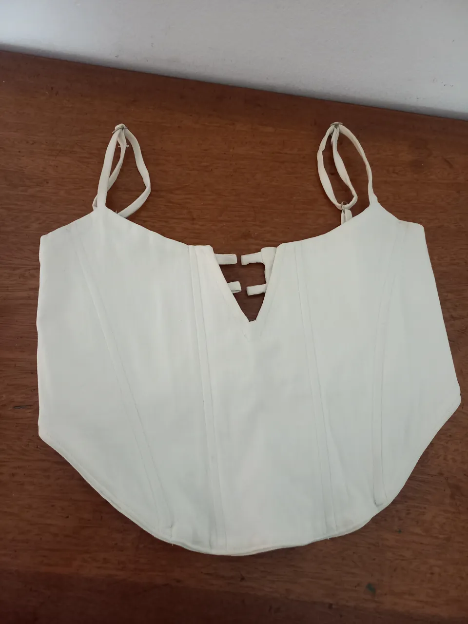 Corpiño estilo corsé blanco, con ballenas y tiras regulables. Ideal para complementar outfits o para usar en eventos especiales. Diseño único con escote en V y detalles de amarre.