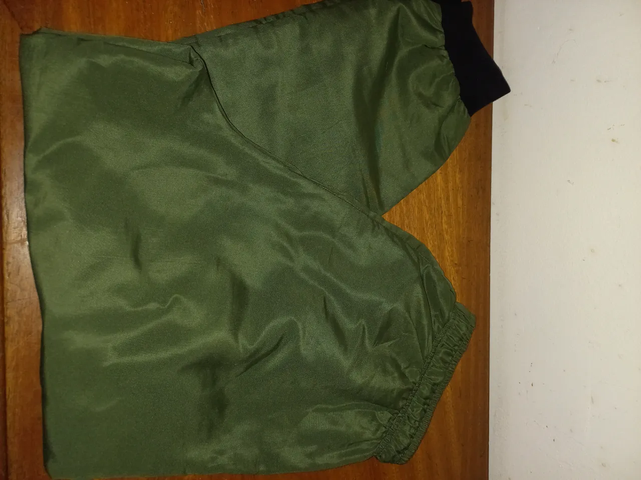 Pantalón de acetato verde militar, con puños y cintura elastizados. Ideal para un look urbano y cómodo.