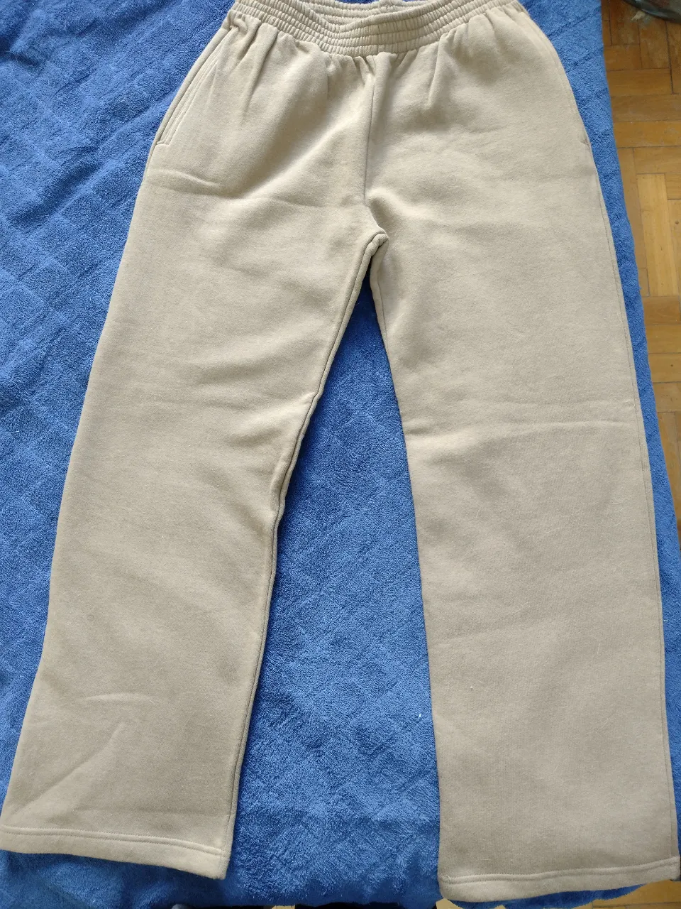 Pantalón de frisa color beige con cintura elastizada y bolsillos laterales. Posee un bolsillo trasero.