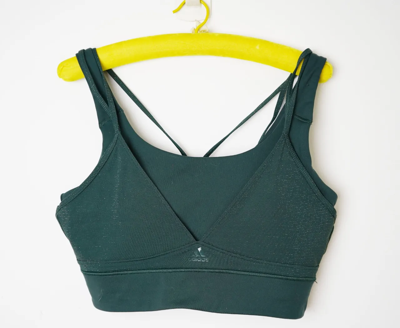 Top deportivo Adidas, color verde oscuro con detalles brillantes. Ideal para entrenamientos o uso casual.