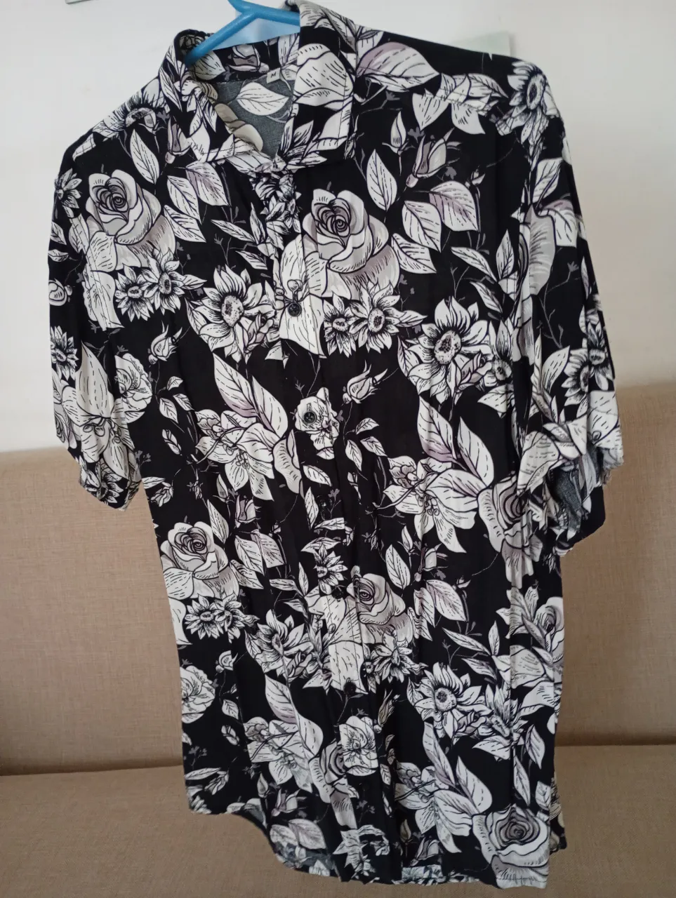 Remera estampada con flores y hojas en blanco y negro. Manga corta y cuello camisero. Ideal para un look casual y fresco.