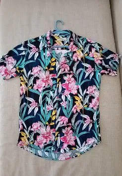 Camisa estampada con flores y hojas en tonos vibrantes. Ideal para un look relajado y con onda. Perfecta para el verano o para darle un toque de color a tu outfit.