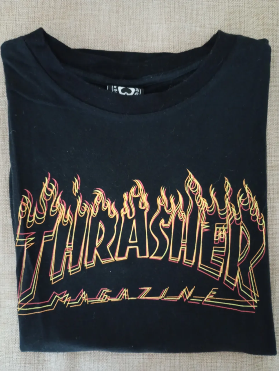 Remera negra de manga corta con estampa de "Thrasher Magazine" en llamas. Un clásico del skatewear, ideal para un look urbano y canchero.