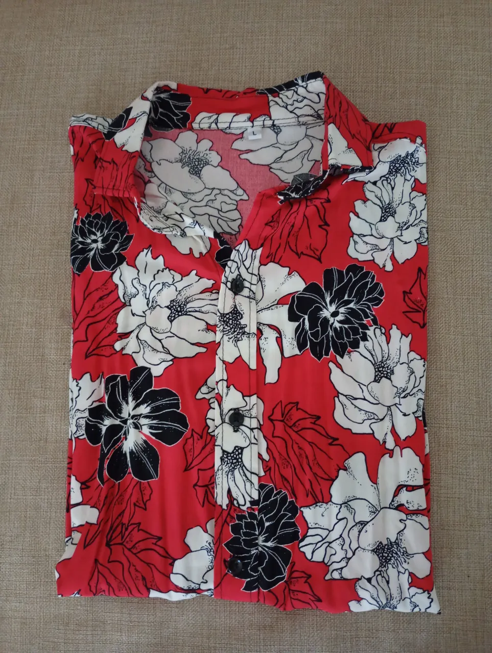 Camisa estampada con flores rojas, blancas y negras. Manga corta, ideal para un look casual y fresco.