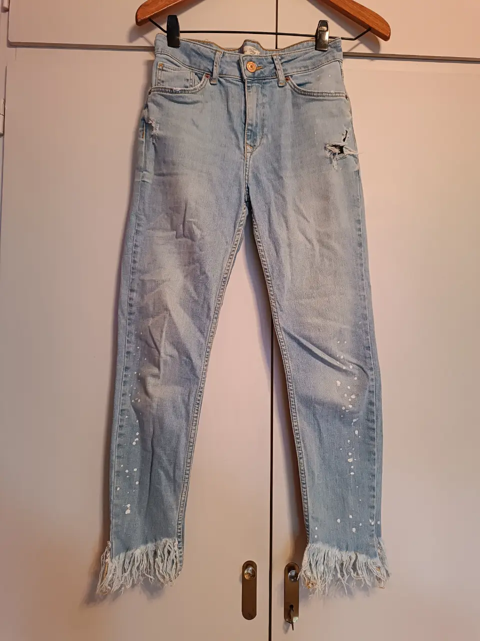 Jeans rectos de mujer Bershka, tiro medio, con detalles de roturas y salpicaduras de pintura blanca. Terminación desflecada en el bajo. Talle 36.