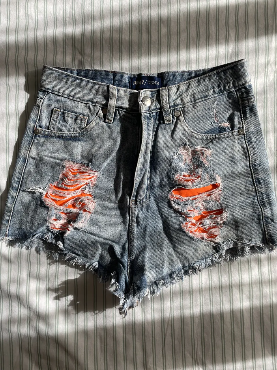 Shorts de jean tiro alto con roturas y bolsillos en naranja. 