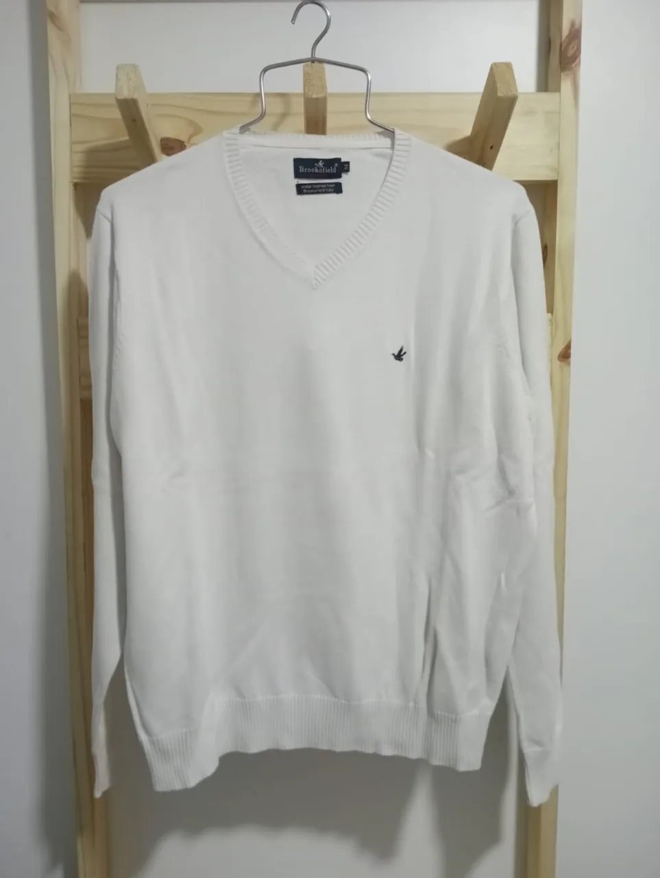 Sweater de hilo blanco talle M, con cuello en V y un pequeño bordado de un pájaro en el frente. Ideal para un look casual y elegante.