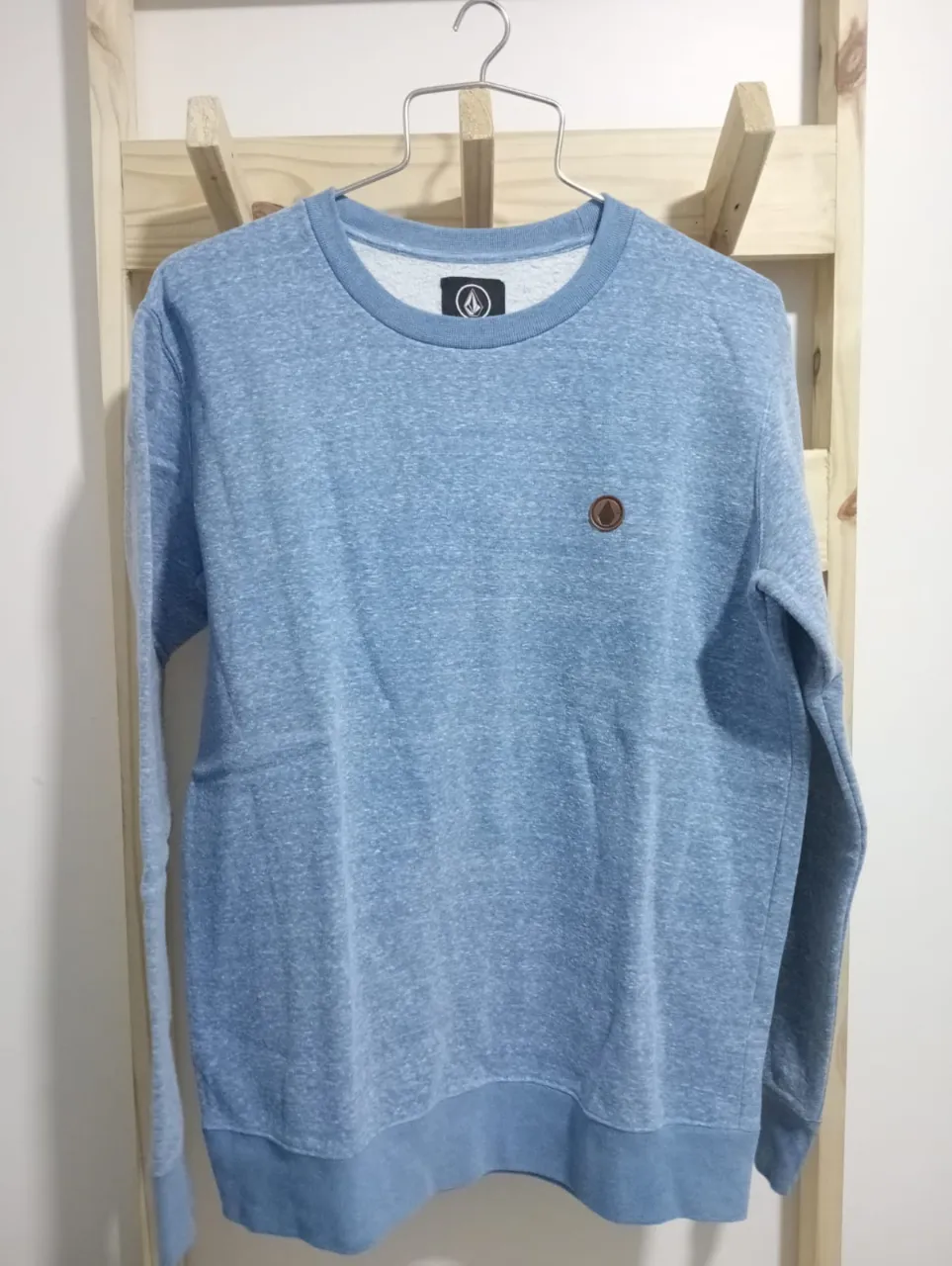 Buzo de algodón color azul claro jaspeado, con cuello redondo y logo de la marca en el pecho. Ideal para un look casual y cómodo.