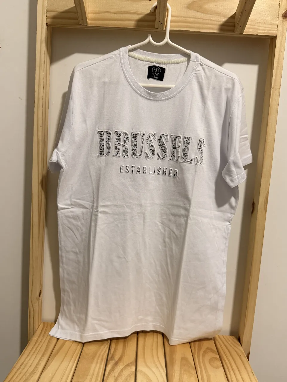 Remera blanca de manga corta con estampa "BRUSSELS ESTABLISHED" en el frente. Ideal para un look casual y moderno.