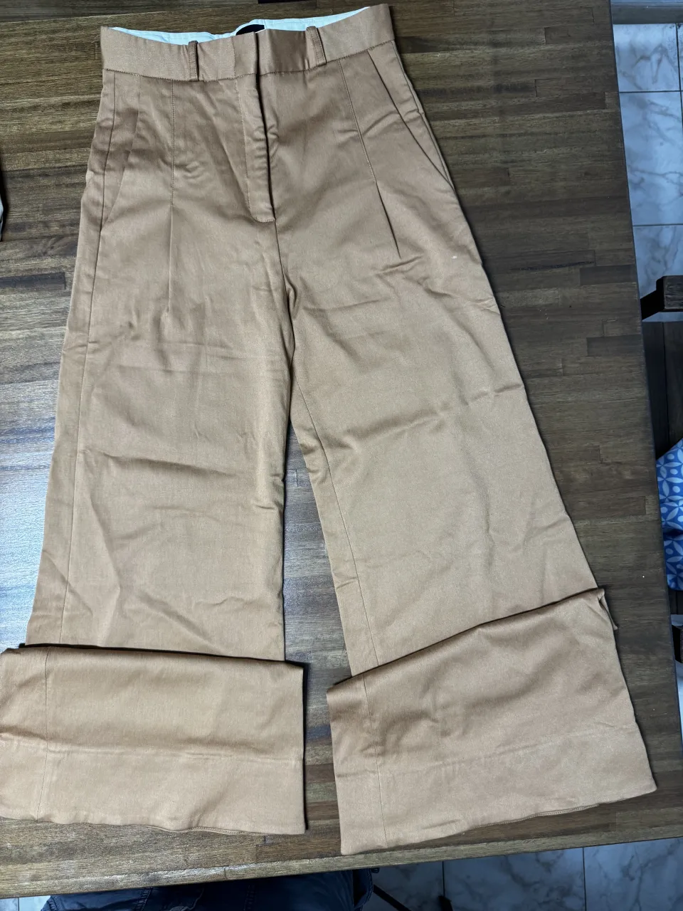 Pantalón ancho de gabardina color caqui, tiro alto, con bolsillos y detalle de puño ancho en el ruedo. Ideal para un look elegante y moderno.