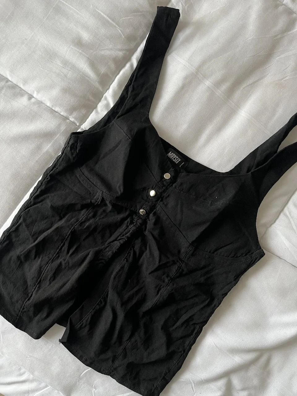 Top negro con breteles anchos y botones decorativos. Ideal para un look moderno y versátil.