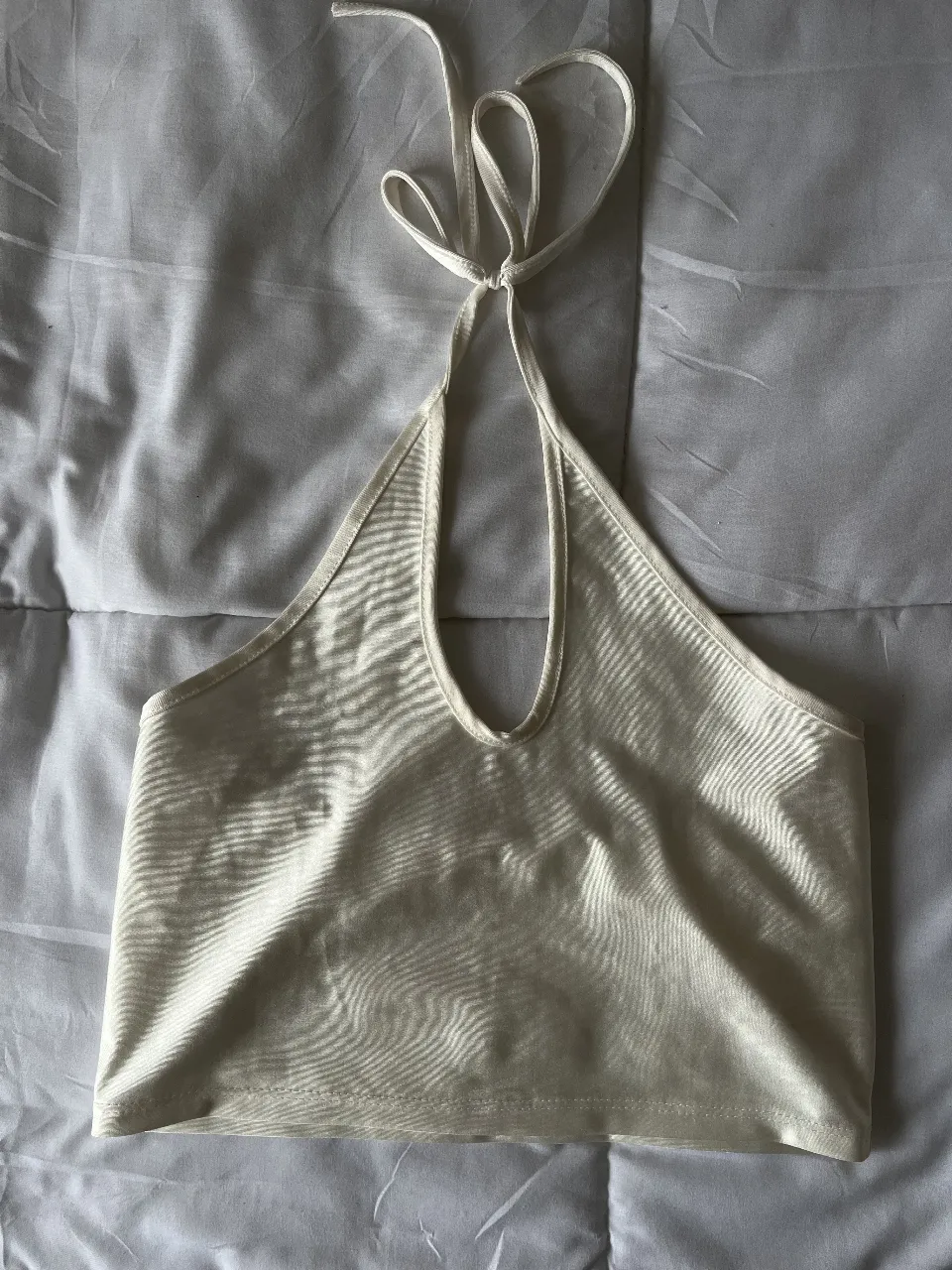 Top halter blanco, ideal para un look fresco y moderno. Perfecto para combinar con jeans o faldas. Un básico versátil para tu guardarropa.