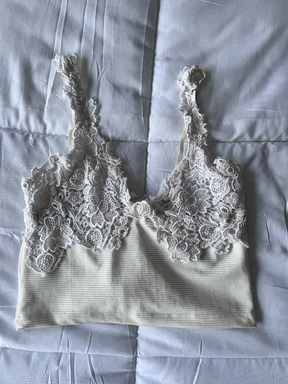 Top blanco con detalles de encaje floral. Ideal para un look romántico y delicado. Perfecto para combinar con faldas o pantalones de tiro alto.