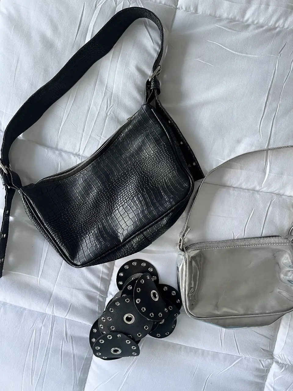Conjunto de cartera y accesorio. Incluye una cartera plateada y un accesorio de cuero negro con detalles metálicos. El valor es por ambas cosas