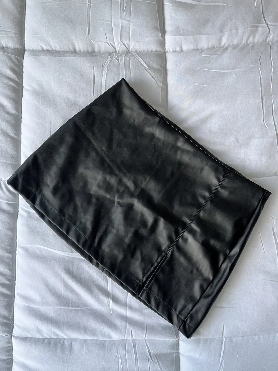 Pollera negra de cuero sintético, ideal para un look elegante y moderno. Tiro Bajo. Confeccionada con un material similar al cuero, esta pollera ofrece un ajuste favorecedor y un estilo versátil. Perfecta para combinar con diferentes tops y calzado, adaptándose a diversas ocasiones. Talle M/L