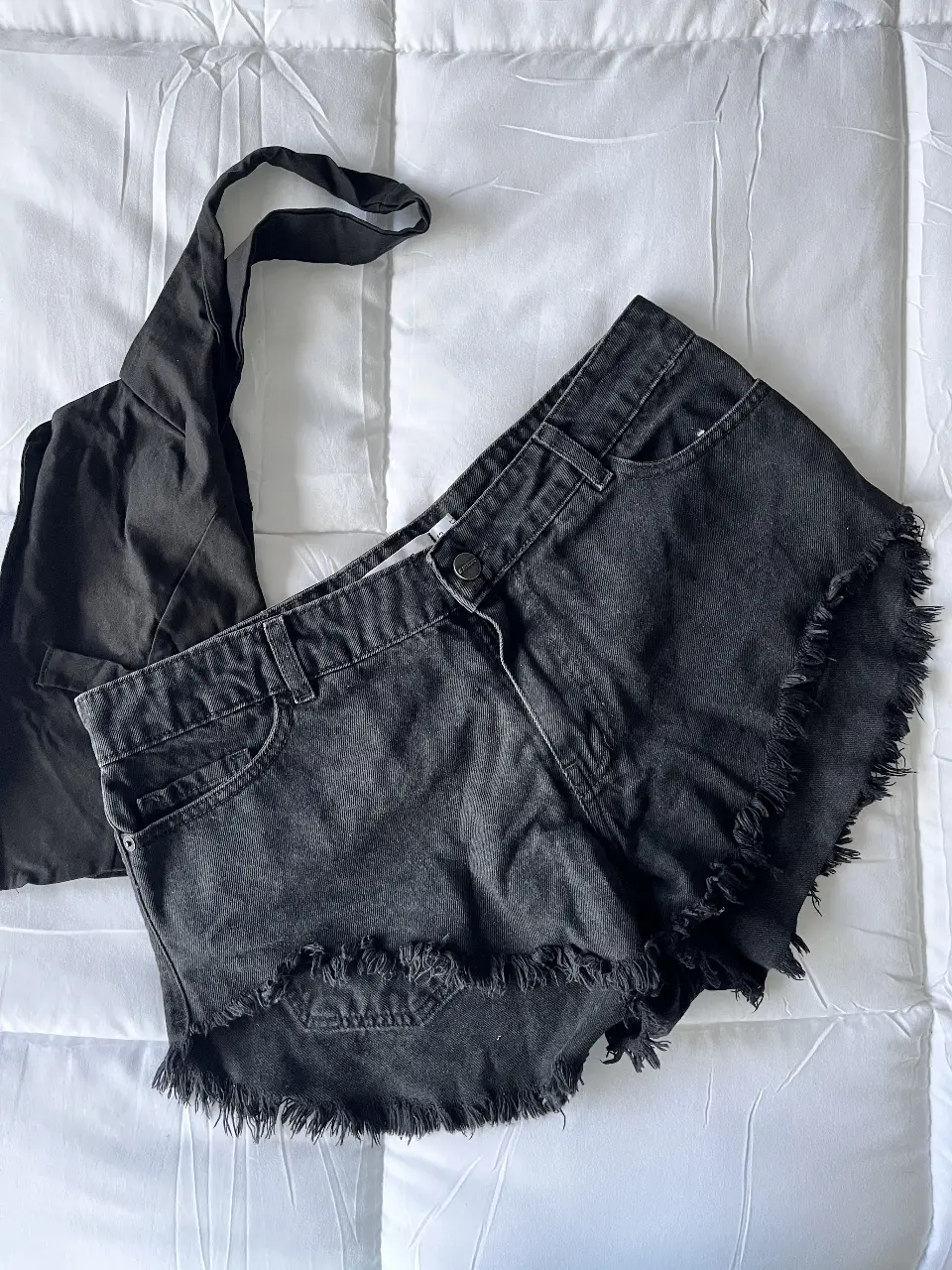 Short de jean negro con flecos en el borde inferior. Tiro bajo, ideal para un look casual y moderno. Perfecto para el verano. Talle 42