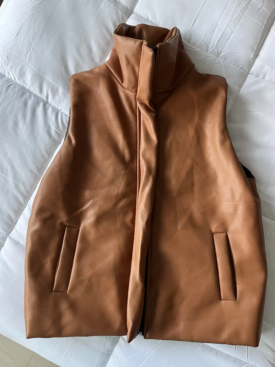 Chaleco de cuero sintético marrón, con cuello alto y cierre. Ideal para un look moderno y abrigado. 