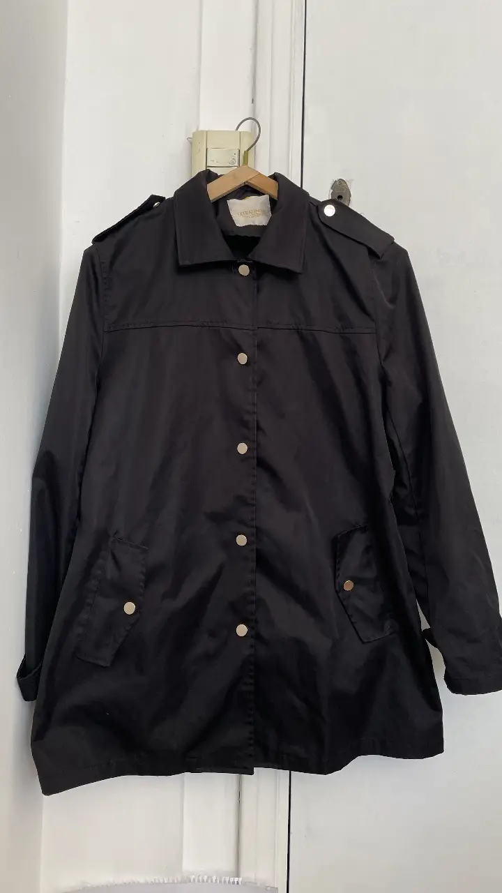 Campera negra de mujer, estilo bomber, con botones dorados y detalles en los hombros. Ideal para un look casual y elegante.