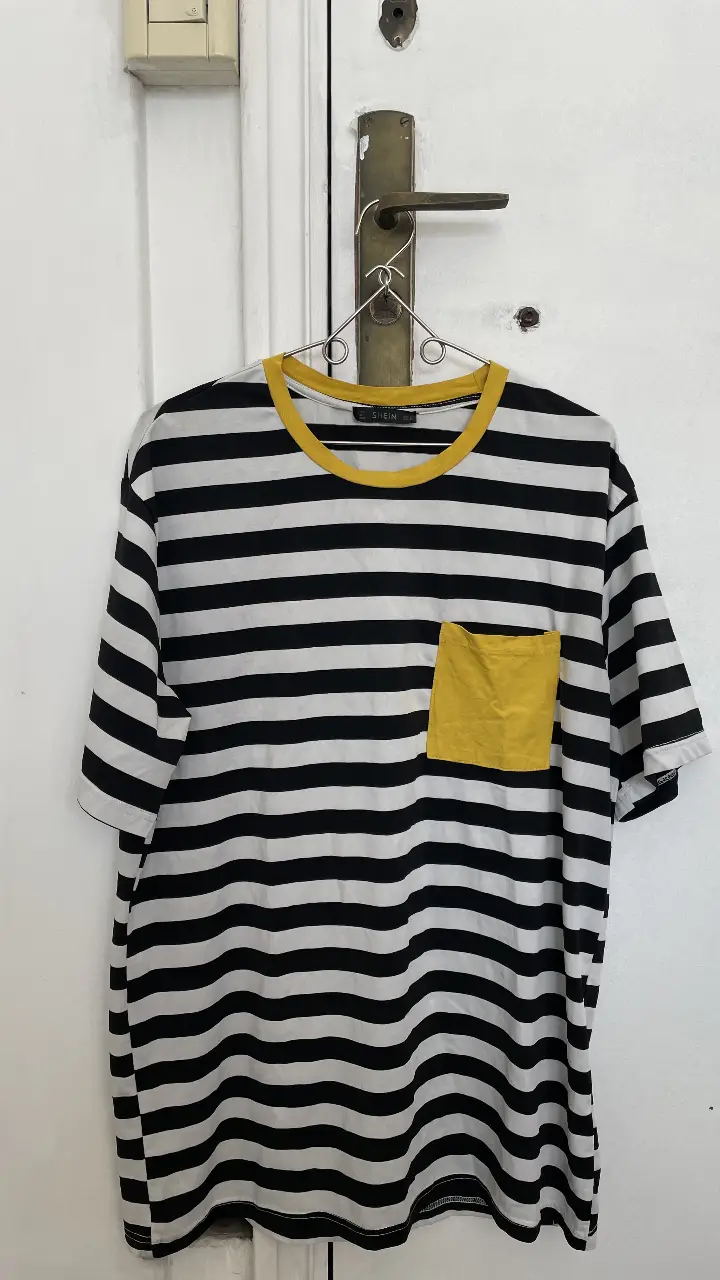 Remera a rayas horizontales en blanco y negro con bolsillo amarillo. Cuello y borde de mangas amarillos. Marca Shein.