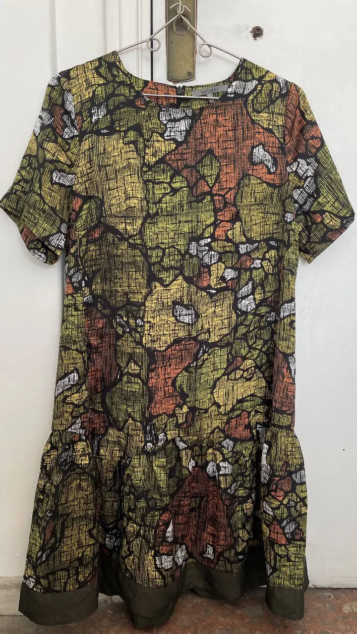 Vestido mini con estampado abstracto en tonos verdes, amarillos, naranjas y negros. Diseño con mangas cortas y detalle de volado en el bajo. Ideal para un look casual y moderno. Es S pero va también para un M.