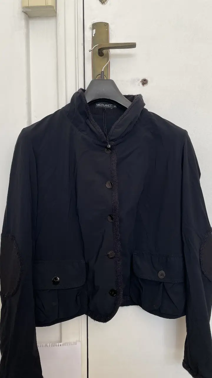 Campera negra de mujer, con cuello alto y botones. Posee dos bolsillos delanteros y detalles en los codos. Ideal para un look casual y moderno.