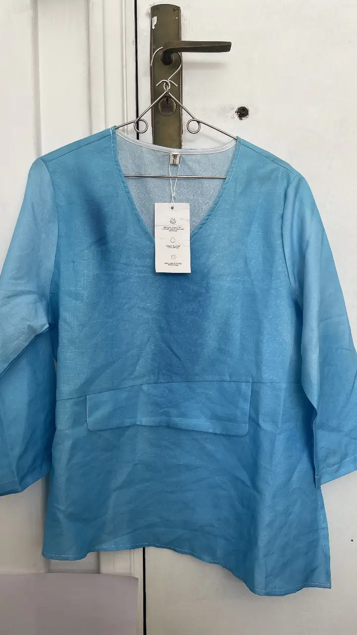 Blusa celeste de lino con cuello en V y bolsillo frontal. Ideal para un look fresco y casual.