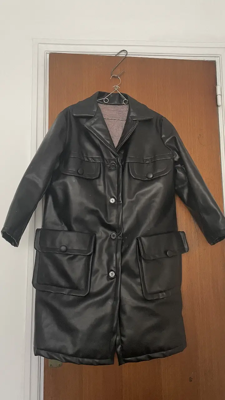 Tapado largo de cuero sintético negro con botones y bolsillos. Ideal para un look moderno y sofisticado.