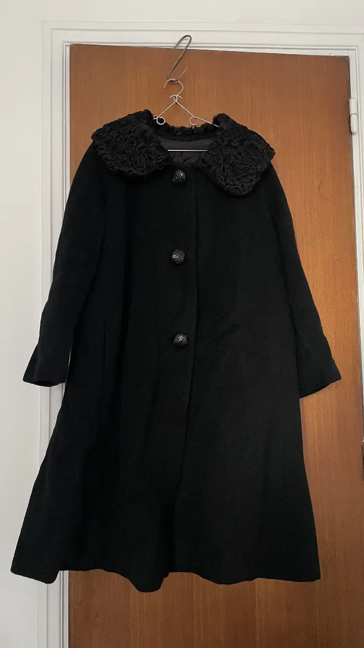 Tapado negro vintage con cuello de piel. Ideal para un look elegante y abrigado en invierno. Cuenta con botones grandes y un diseño clásico.
