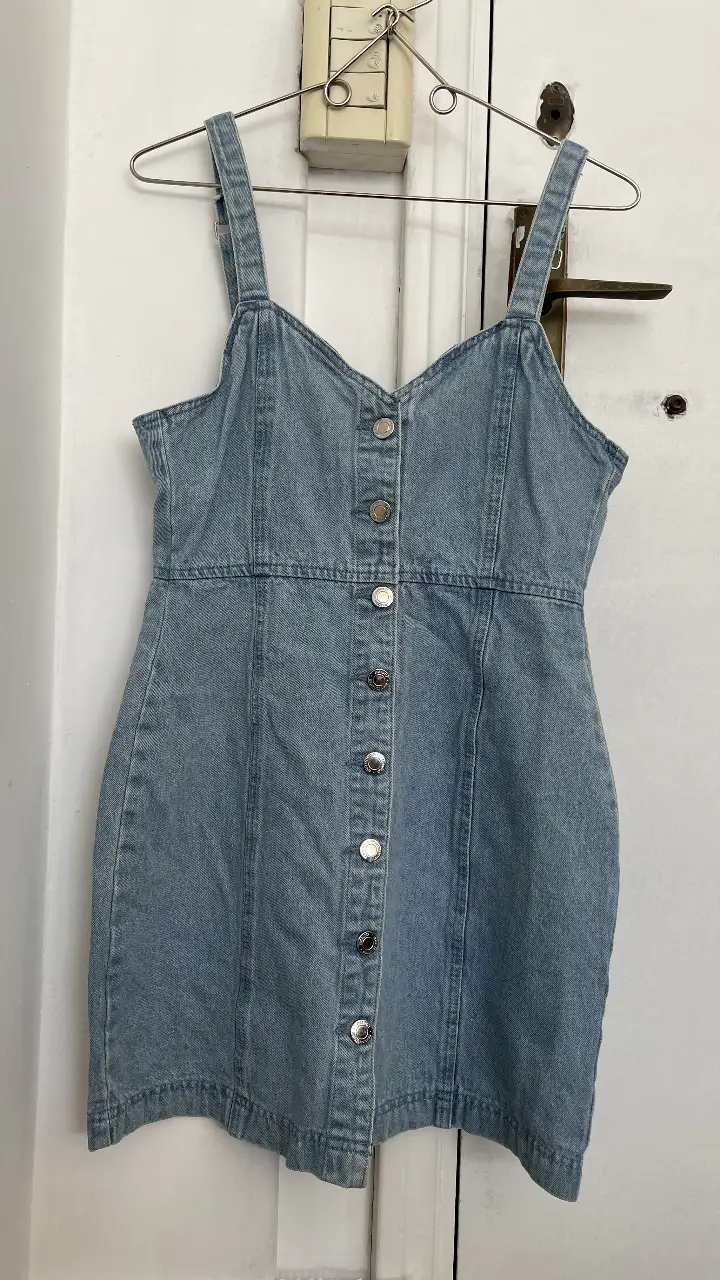Vestido mini de jean azul claro, con botones frontales y tirantes. Ideal para un look casual y fresco.