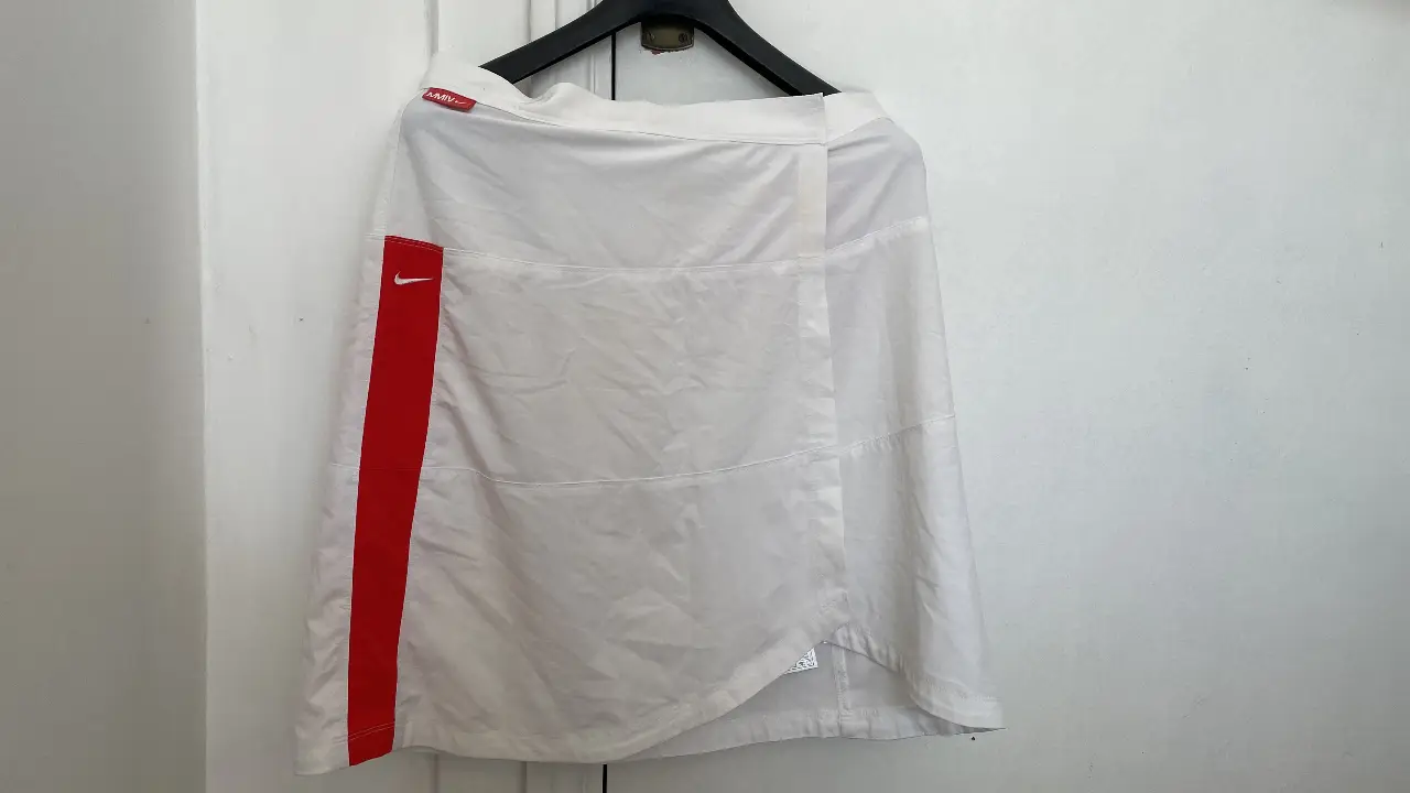 Pollera deportiva blanca con detalle rojo en el lateral. Ideal para actividades físicas.