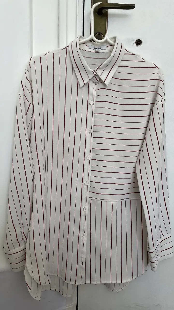 Camisa a rayas en blanco y rojo, con diseño asimétrico. Marca Nicopoly. Ideal para un look casual y moderno.