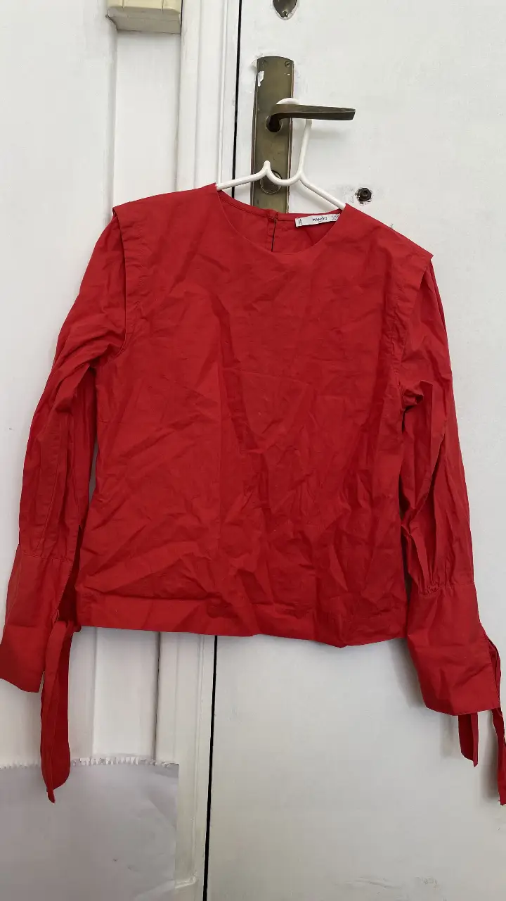 Blusa roja de manga larga con detalles en los hombros y lazos en los puños. Ideal para un look elegante y moderno.