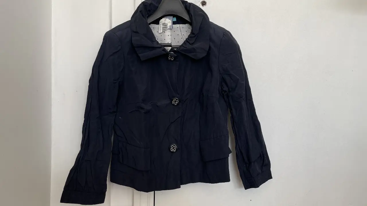 Chaqueta negra de mujer, de la marca RIANI. Con botones decorativos y forro interior con lunares. Ideal para un look elegante y sofisticado.