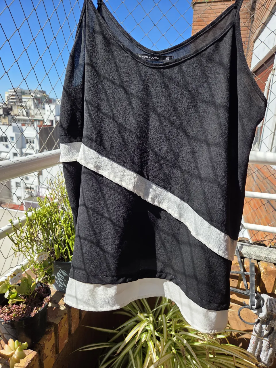Top negro con detalles blancos. Ideal para un look moderno y versátil. Perfecto para combinar con jeans o faldas.