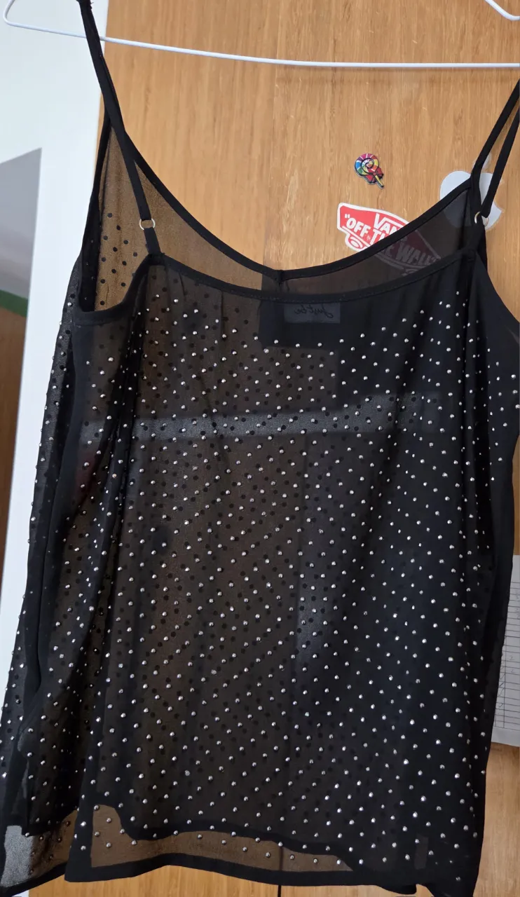 Top negro transparente con detalles brillantes. Ideal para fiestas o salidas nocturnas. Estilo moderno y audaz.