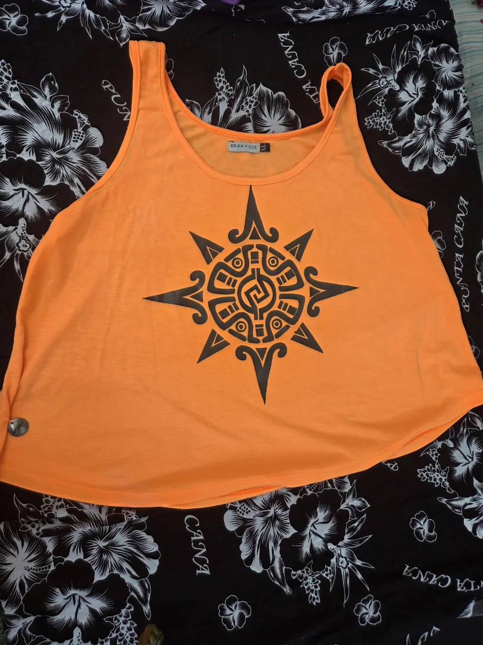 Musculosa naranja vibrante con un llamativo estampado de sol estilo azteca en negro. Perfecta para un look relajado y con onda.