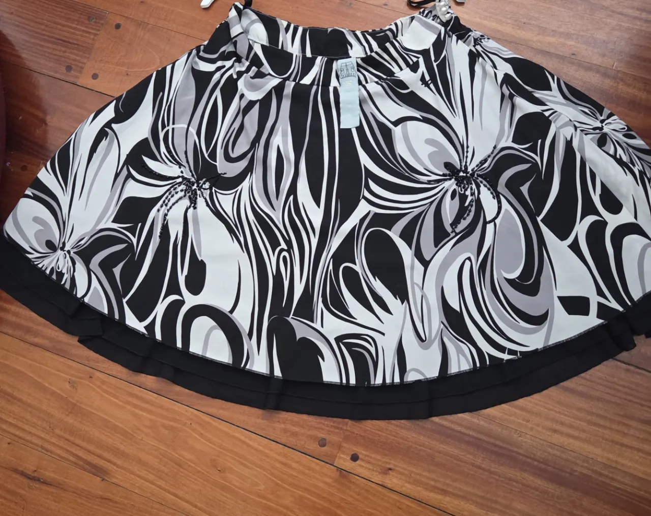 Pollera larga de mujer con estampado floral en blanco y negro. Diseño con vuelo y detalle de volado en el borde inferior. Ideal para un look elegante y fresco.