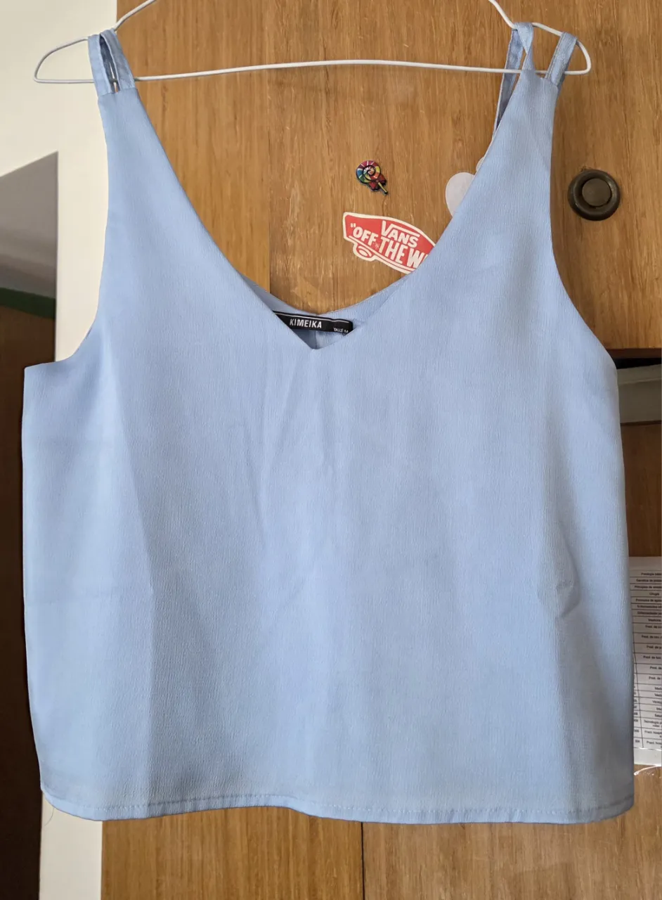 Top de mujer celeste con escote en V y tiras finas. Ideal para un look fresco y casual.