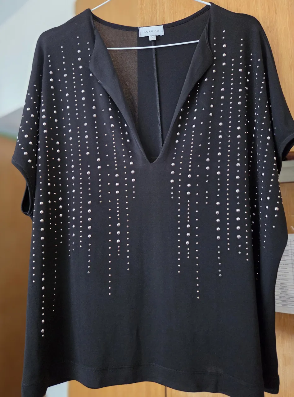Blusa negra con detalles de strass plateados. Cuello en V y mangas cortas. Ideal para una salida o evento especial.