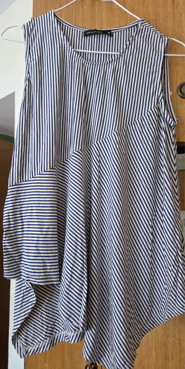 Remera sin mangas de mujer con estampado a rayas verticales en azul y blanco. Diseño asimétrico y moderno, ideal para un look fresco y casual.