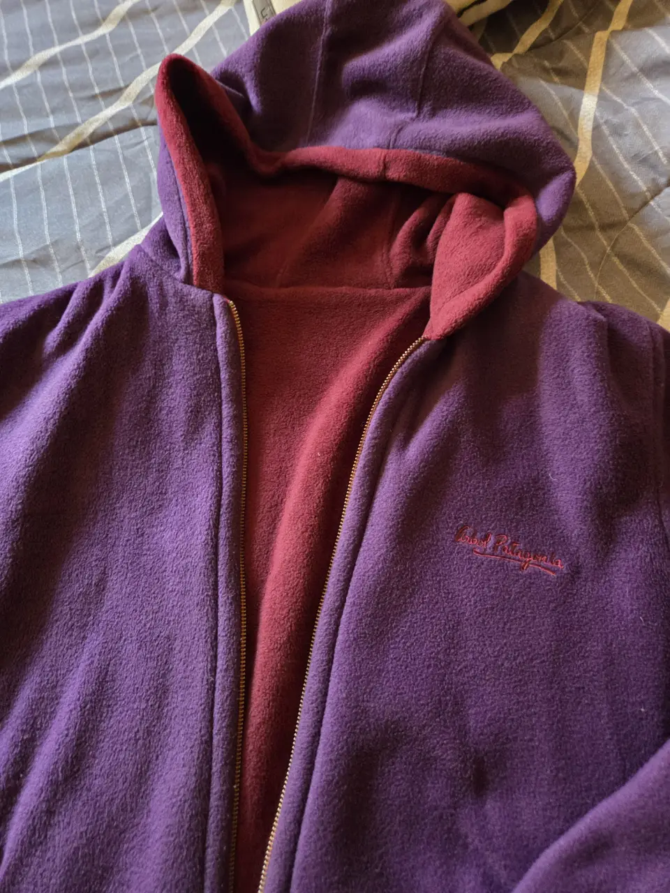 Buzo con cierre reversible, de color violeta por fuera y rojo por dentro. Ideal para el invierno, con capucha y bolsillos.