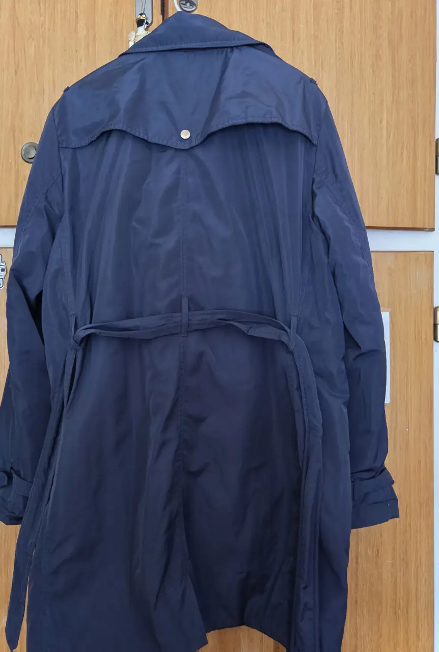 Trench coat azul marino para mujer, con cinturón y detalles clásicos. Ideal para un look elegante y versátil.