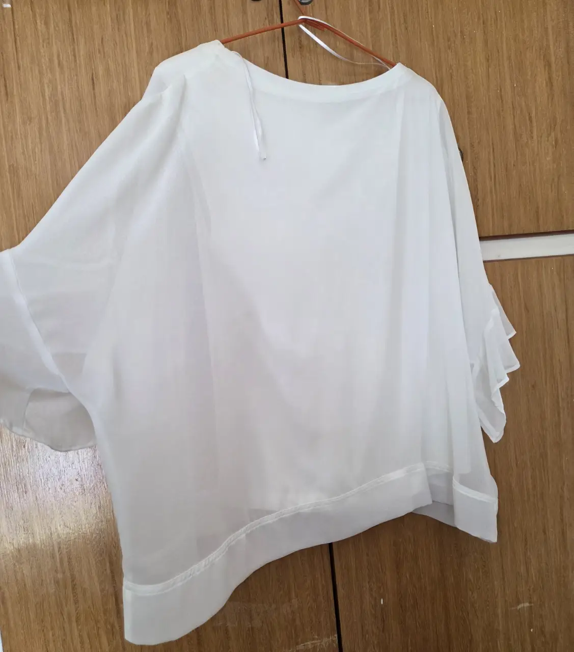 Blusa blanca de tela liviana y fluida, con mangas amplias y detalles de volados. Ideal para un look fresco y elegante.