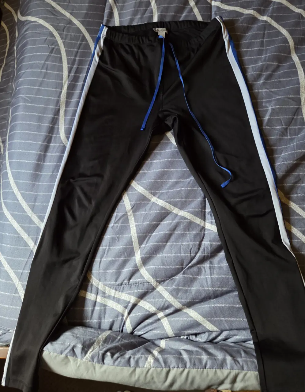 Pantalón deportivo negro con franjas blancas y detalles azules. Ideal para actividades físicas o un look casual.