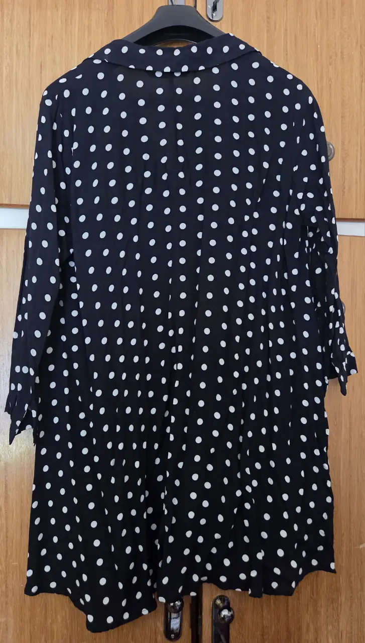 Blusa de mujer con estampado de lunares blancos sobre fondo negro. Manga larga con puños y cuello camisero. Ideal para un look casual o de trabajo.